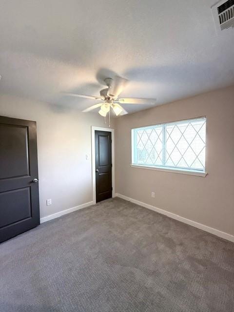 carpeted spare room with ceiling fan, visible vents, and baseboards