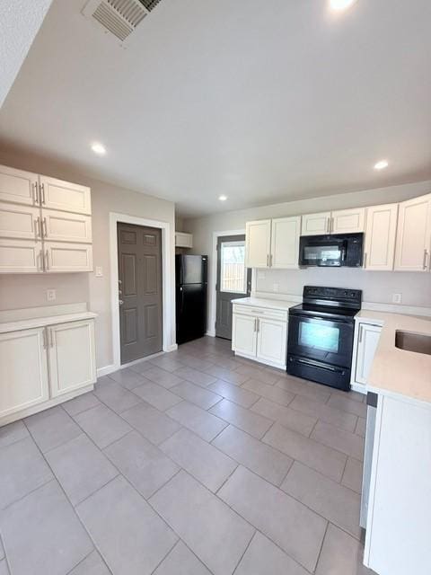 kitchen featuring white cabinets, black appliances, visible vents, and light countertops