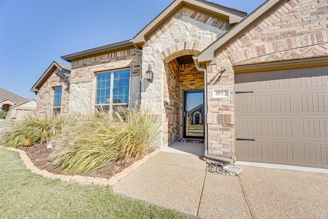 doorway to property with stone siding, brick siding, and an attached garage