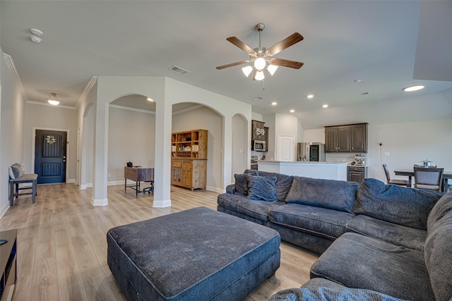 living room featuring arched walkways, baseboards, visible vents, and light wood-style floors