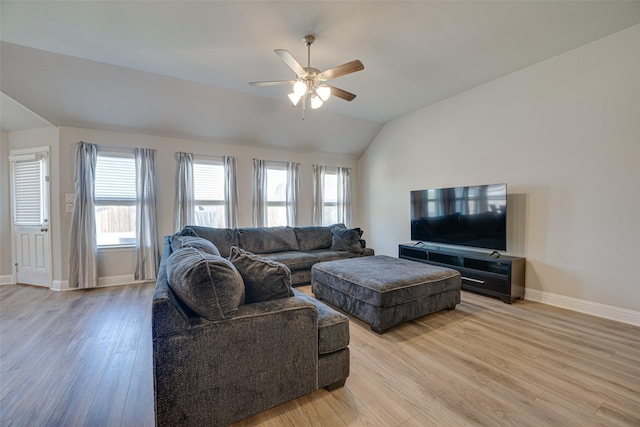 living room with light wood-type flooring, a healthy amount of sunlight, baseboards, and lofted ceiling