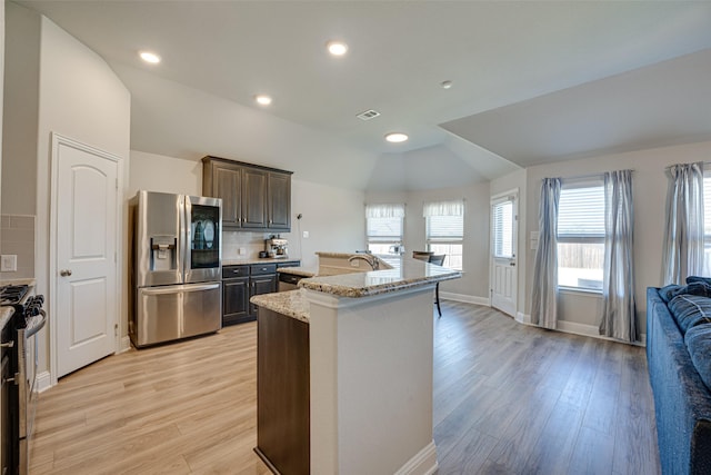 kitchen featuring lofted ceiling, light wood-style flooring, open floor plan, gas range, and stainless steel fridge