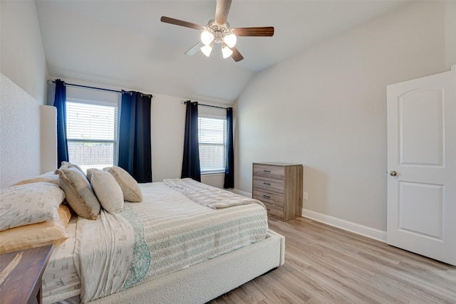 bedroom with lofted ceiling, light wood-style flooring, multiple windows, and baseboards