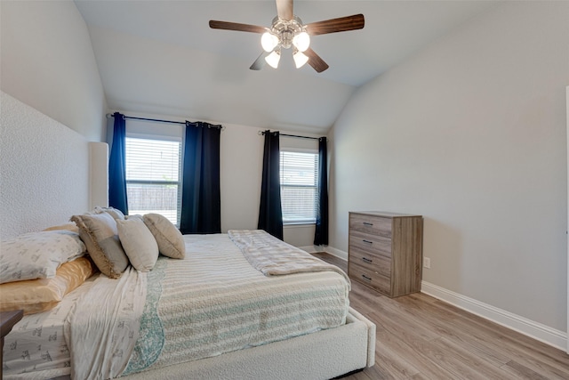 bedroom with light wood-type flooring, lofted ceiling, multiple windows, and baseboards