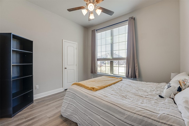 bedroom with ceiling fan, wood finished floors, and baseboards