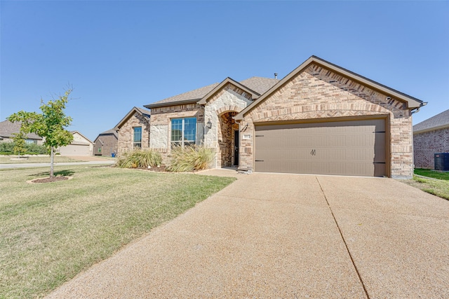 french country home with central AC unit, an attached garage, brick siding, driveway, and a front yard