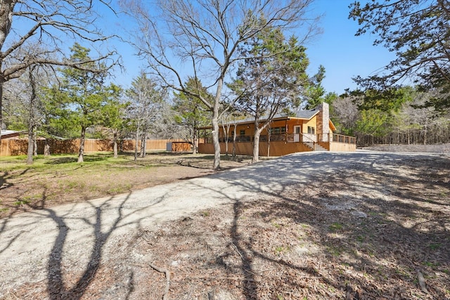 view of front of property featuring driveway, a porch, a chimney, and fence