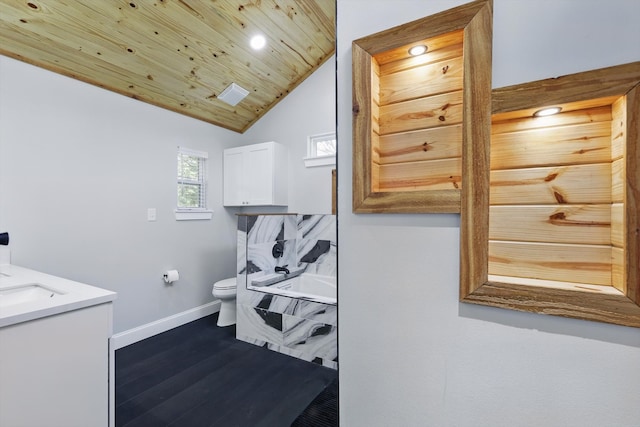 full bath with lofted ceiling, wood finished floors, toilet, a bathing tub, and baseboards