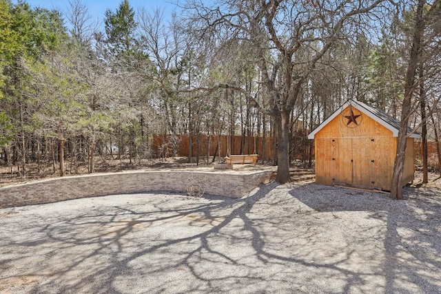 view of yard featuring fence, an outdoor structure, and a storage shed
