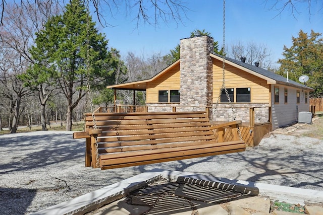 back of property with central AC, a chimney, and a deck