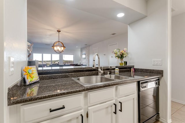 kitchen featuring white cabinets, dishwashing machine, dark stone countertops, pendant lighting, and a sink