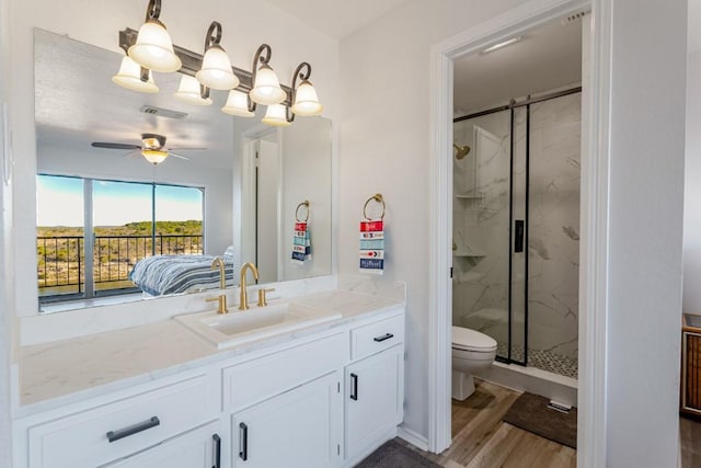 bathroom featuring a marble finish shower, visible vents, toilet, wood finished floors, and vanity