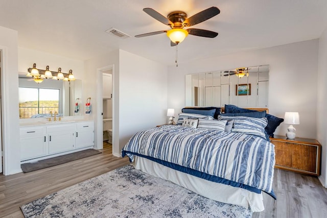 bedroom featuring light wood finished floors, a sink, visible vents, and a ceiling fan