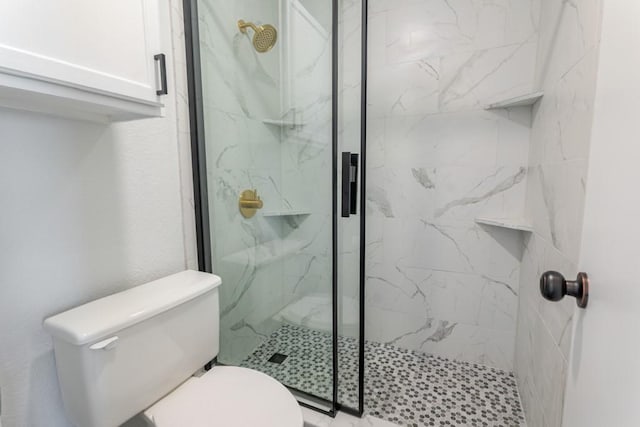 bathroom featuring toilet and a marble finish shower