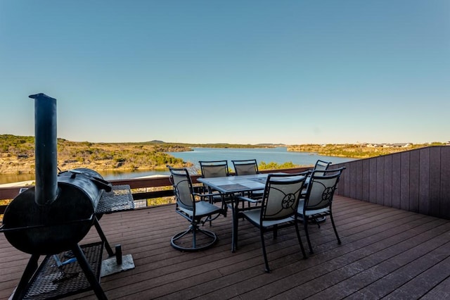 deck with outdoor dining space and a water view