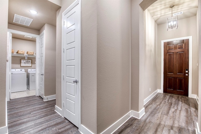 hall featuring independent washer and dryer, wood finished floors, visible vents, and baseboards