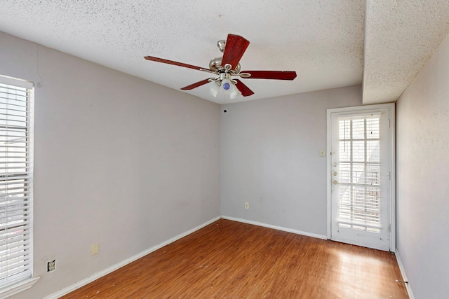 spare room with ceiling fan, baseboards, a textured ceiling, and wood finished floors