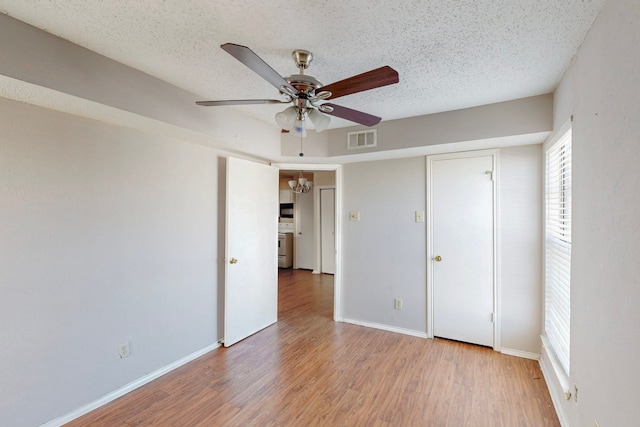 unfurnished bedroom with visible vents, a textured ceiling, light wood-style floors, baseboards, and ceiling fan