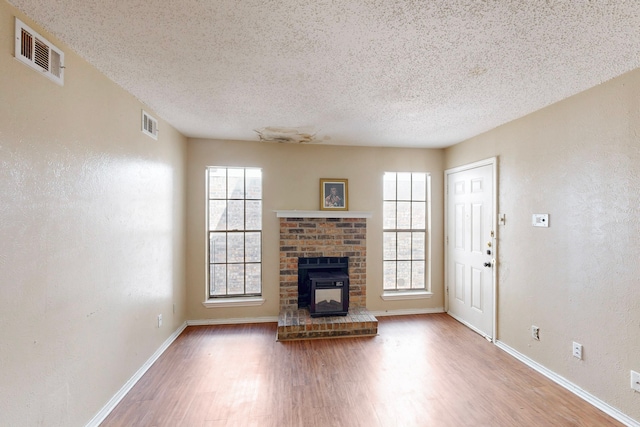 unfurnished living room featuring wood finished floors, visible vents, and a textured ceiling