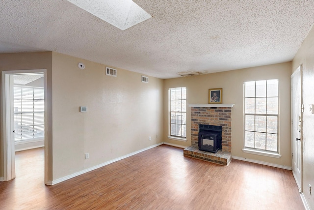 unfurnished living room featuring a brick fireplace, wood finished floors, and visible vents