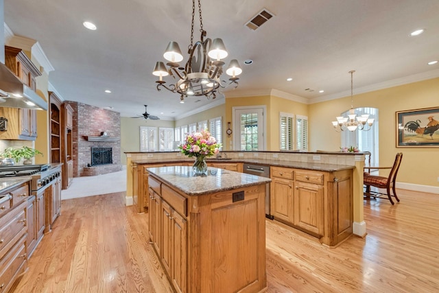 kitchen featuring a spacious island, stainless steel appliances, visible vents, ornamental molding, and a brick fireplace