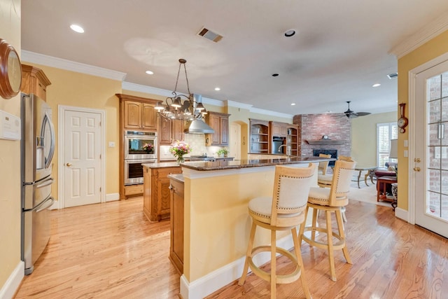 kitchen with an island with sink, light wood-style floors, appliances with stainless steel finishes, and visible vents