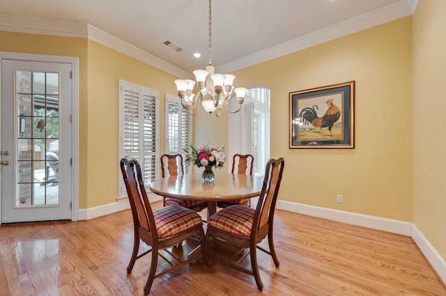 dining area with ornamental molding, light wood-type flooring, visible vents, and baseboards