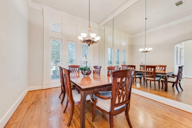 dining area featuring arched walkways, visible vents, baseboards, light wood finished floors, and an inviting chandelier