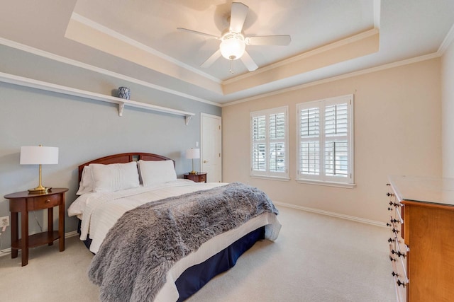 carpeted bedroom featuring ornamental molding, a tray ceiling, ceiling fan, and baseboards