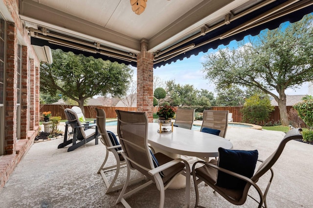 view of patio with outdoor dining area, a fenced backyard, and a fenced in pool