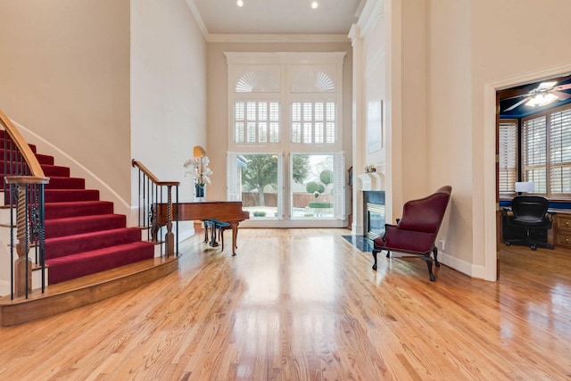 sitting room with crown molding, a high ceiling, baseboards, and wood finished floors