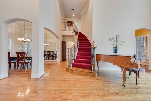 foyer entrance with a notable chandelier, stairway, a high ceiling, ornamental molding, and wood finished floors