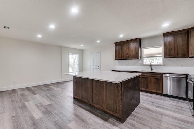 kitchen featuring a center island, light countertops, stainless steel dishwasher, light wood-style floors, and a sink