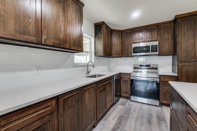 kitchen with stainless steel appliances, a sink, light countertops, dark brown cabinets, and tasteful backsplash