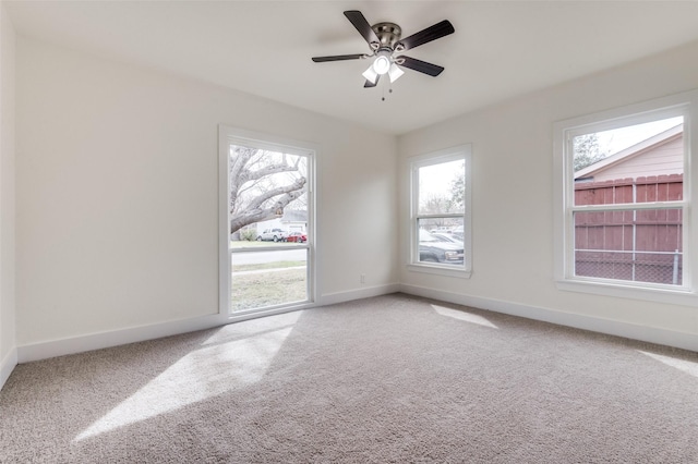 carpeted empty room with a ceiling fan and baseboards