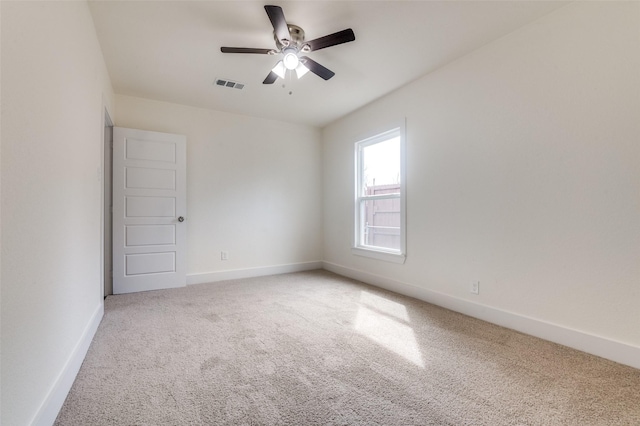 carpeted spare room with a ceiling fan, visible vents, and baseboards