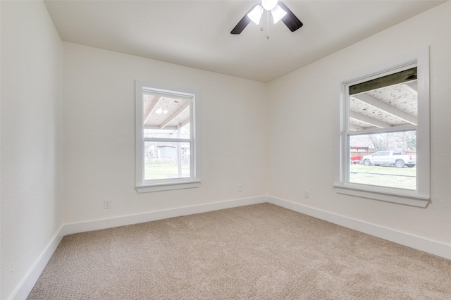 carpeted spare room with a ceiling fan and baseboards