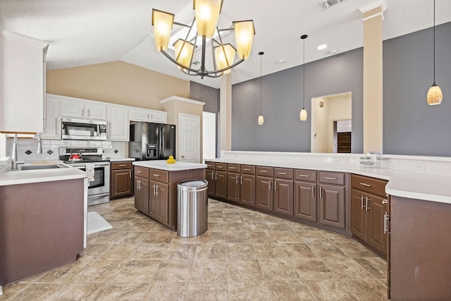 kitchen with lofted ceiling, a center island, stainless steel appliances, light countertops, and white cabinetry