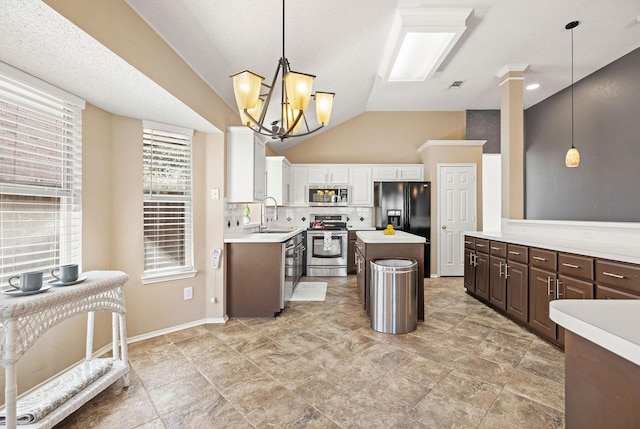 kitchen featuring tasteful backsplash, light countertops, appliances with stainless steel finishes, vaulted ceiling, and a kitchen island