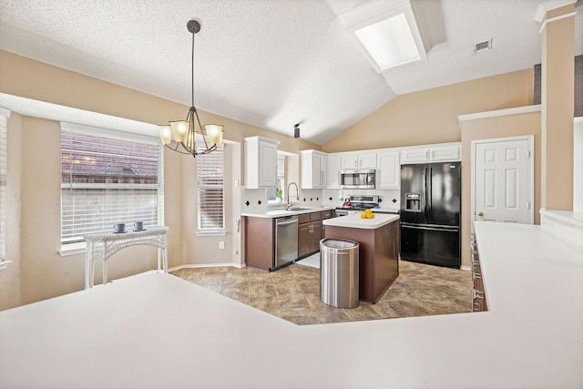 kitchen with visible vents, lofted ceiling, appliances with stainless steel finishes, white cabinetry, and a sink