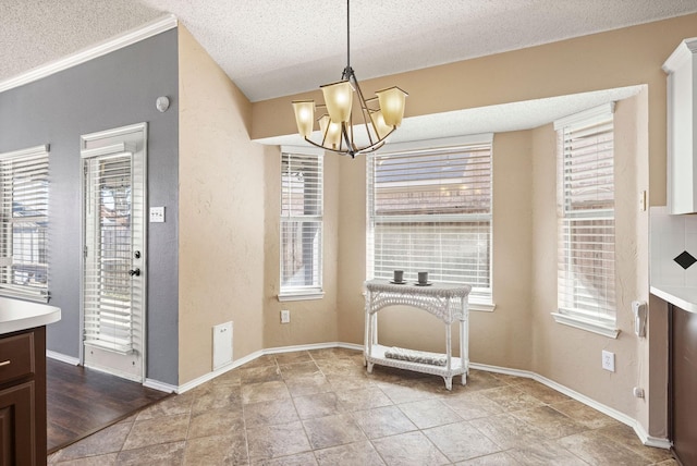 dining space with a textured ceiling, a textured wall, baseboards, and a notable chandelier