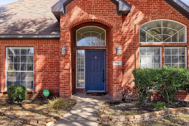 property entrance with brick siding and roof with shingles