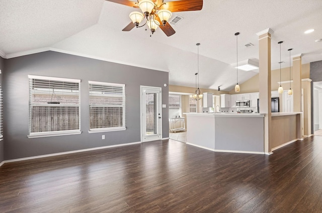 unfurnished living room with lofted ceiling, ceiling fan with notable chandelier, visible vents, baseboards, and dark wood finished floors