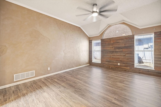 spare room featuring lofted ceiling, visible vents, wood finished floors, and ornamental molding