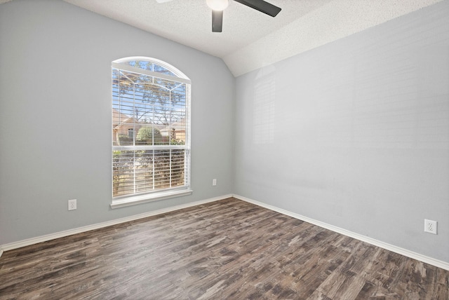 spare room with lofted ceiling, dark wood-type flooring, ceiling fan, a textured ceiling, and baseboards