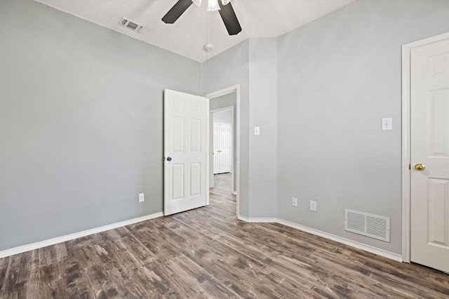 spare room with ceiling fan, wood finished floors, visible vents, and baseboards