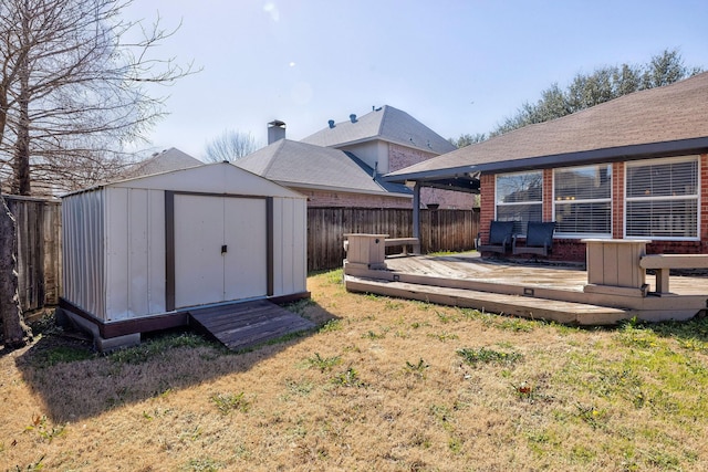 view of yard featuring a storage shed, a fenced backyard, a deck, and an outdoor structure