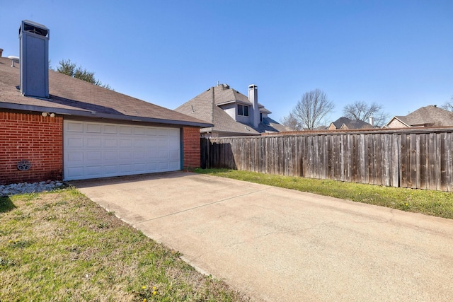 view of property exterior featuring an attached garage, brick siding, fence, concrete driveway, and a chimney