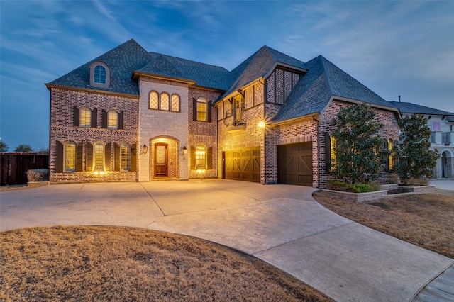 french country style house featuring a garage, concrete driveway, brick siding, and a shingled roof