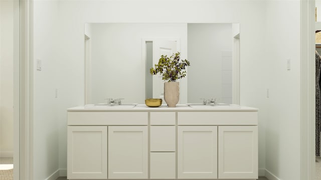 full bathroom featuring double vanity, baseboards, and a sink